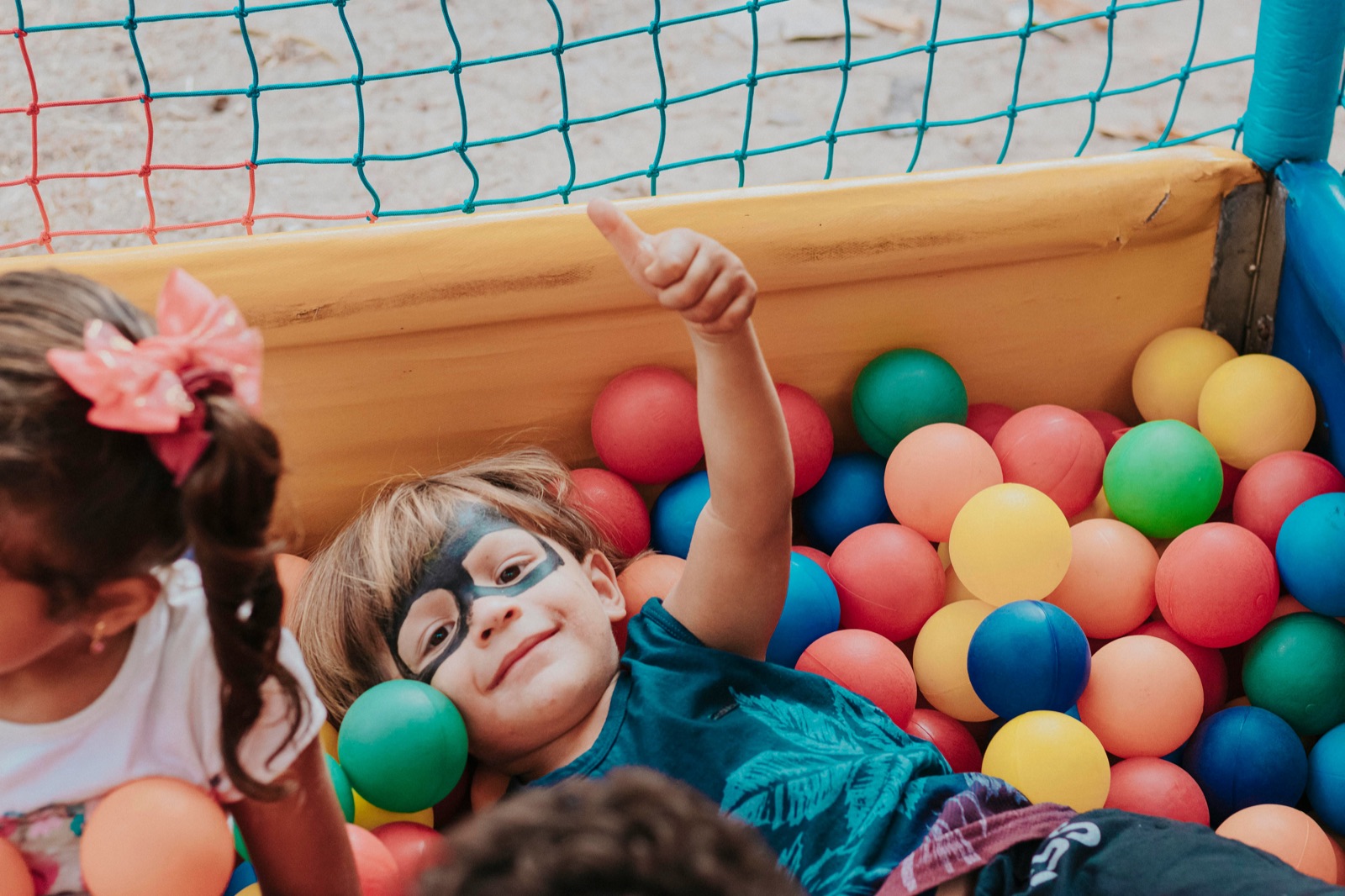 A kid giving a thumbs up while playing in a ball pit